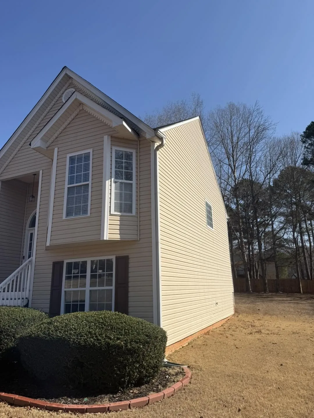 Two-story tan-sided home in Villa Rica shot from the front yard, side gable elevation, clean siding under a blue winter sky