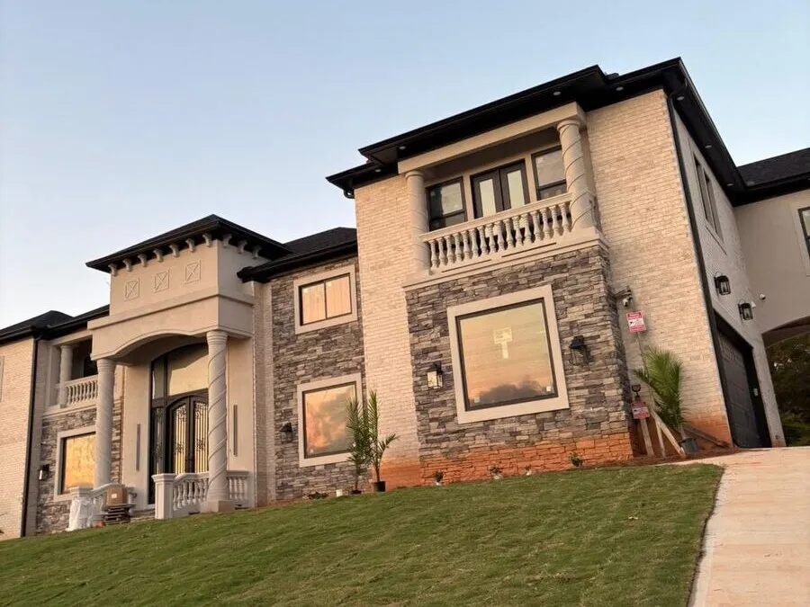 New construction stone and stucco home at sunset with fresh sod after a gutter install in West Georgia