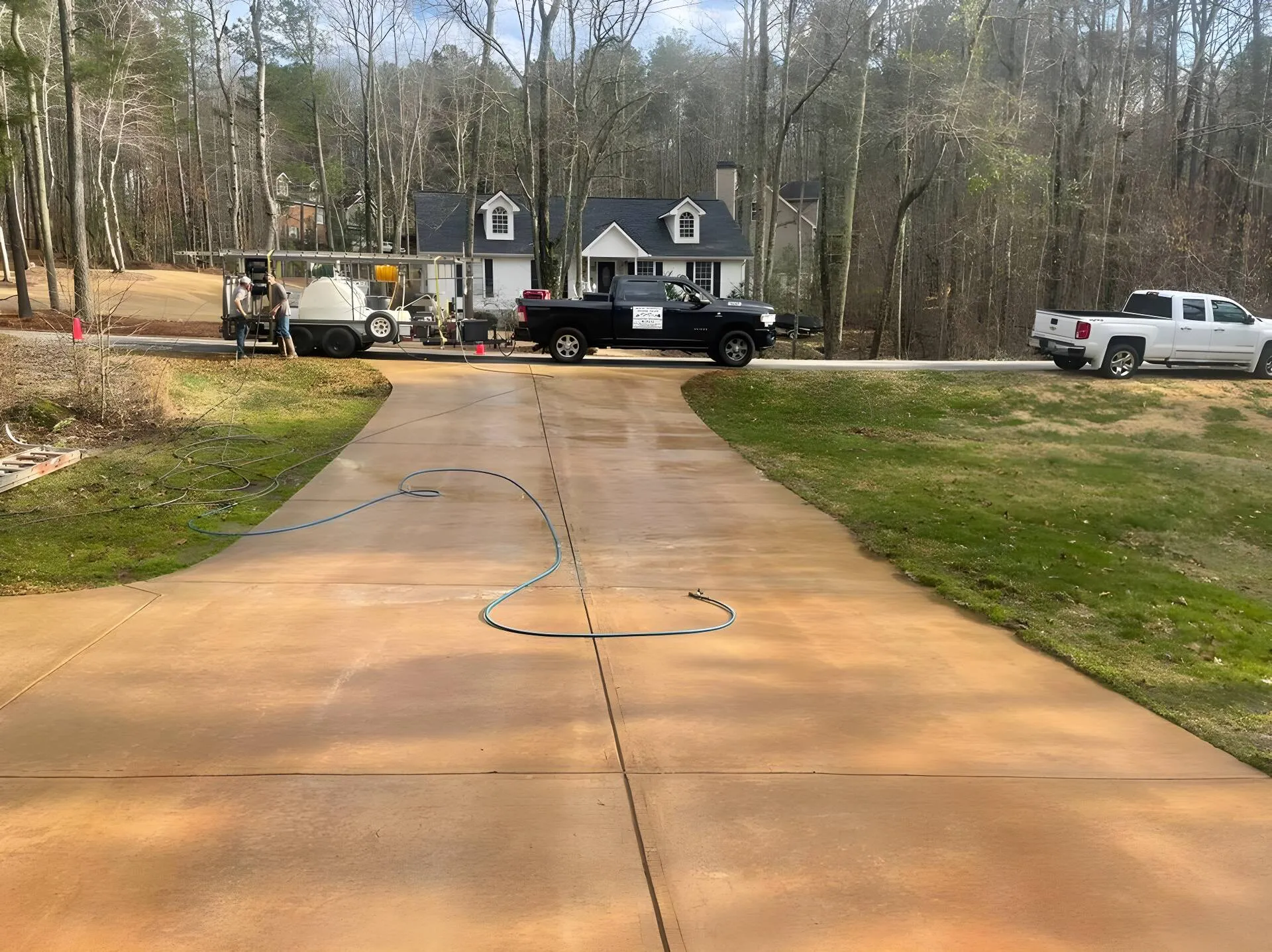 West Georgia Gutter Guys pickup truck and pressure washing trailer rig parked on a residential driveway, two crew members at the trailer