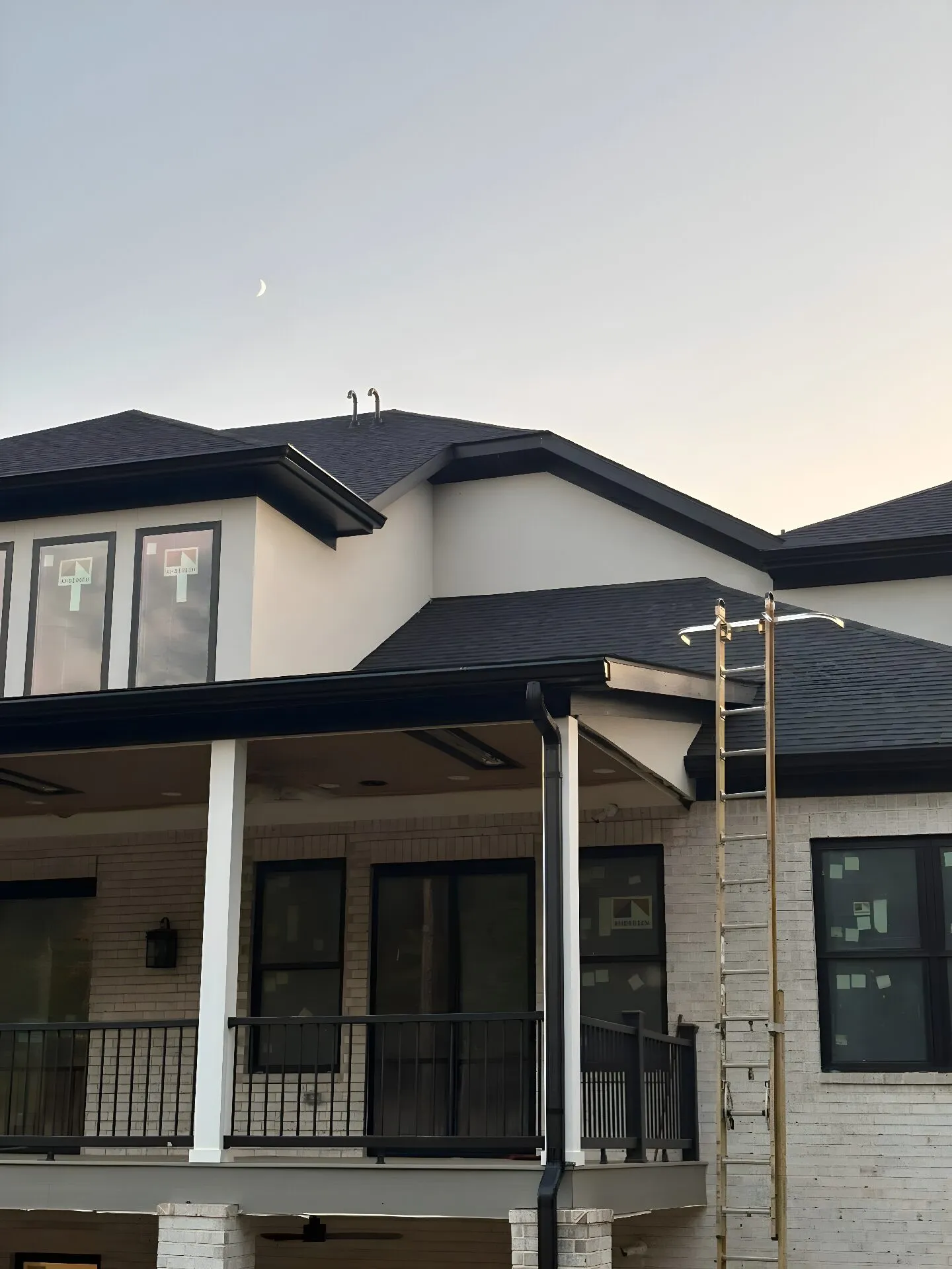 Seamless gutter installed along a new construction roofline at dusk in West Georgia, ladder still in place